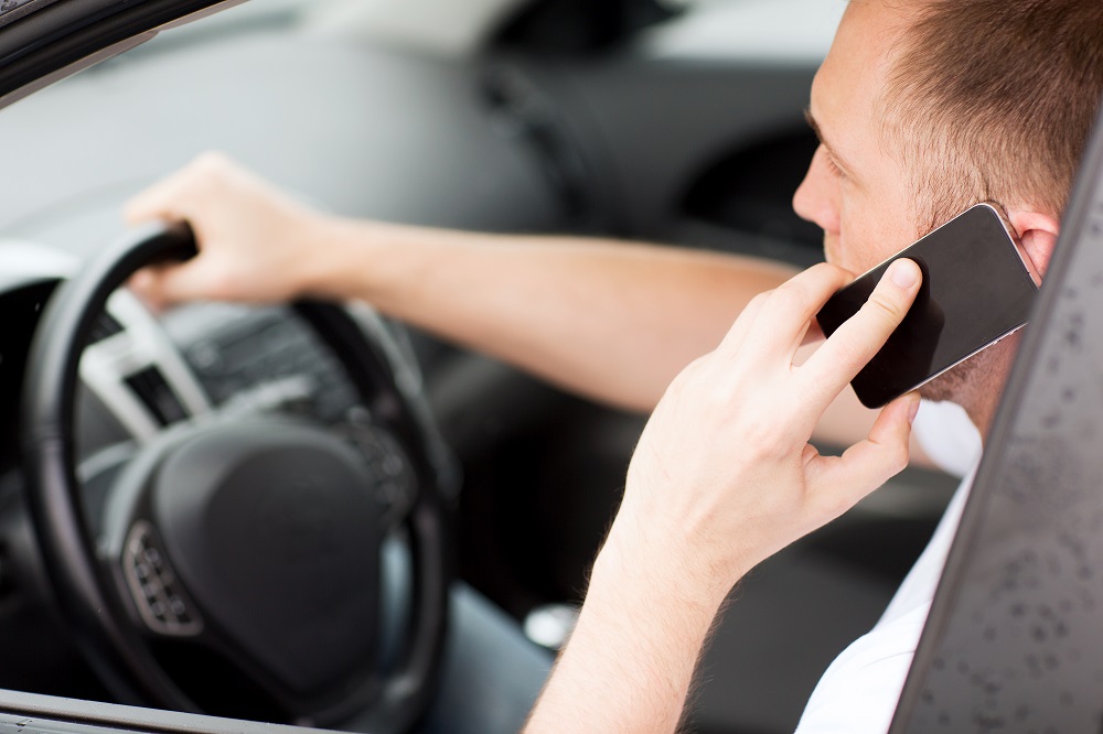 Man is using his phone calling while driving.