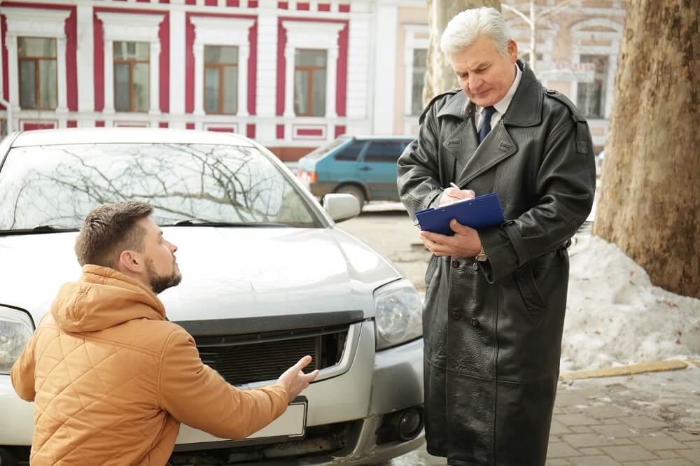 Insurance adjuster checking on damaged car.