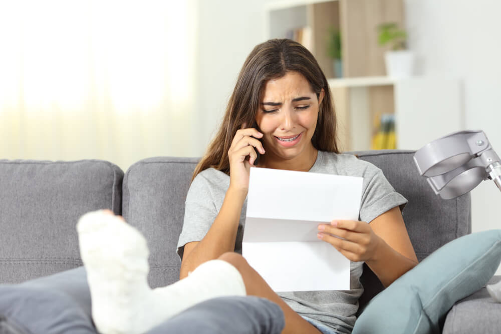 Injured woman crying while reading denied claims.