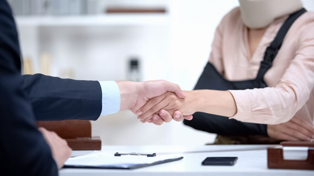 Injured worker handshaking with workers comp lawyer