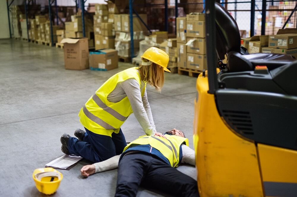 Female coworker helping her injured colleague on the warehouse site.