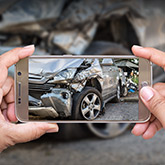 person taking photos of car accident with cell phone