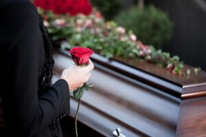 A widow, holding a red rose, grieving at her partner's funeral
