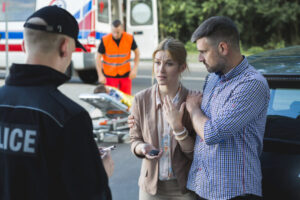 man and woman speaking with police after a car accident