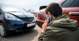 man calling for help on his phone after a car wreck