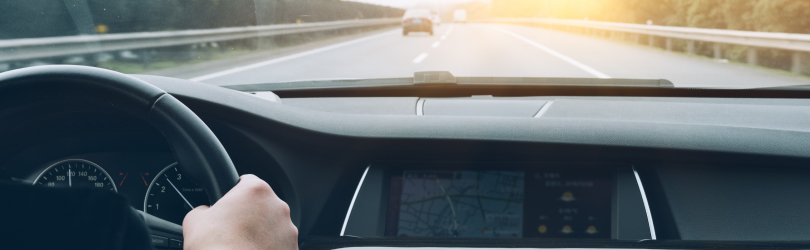 person driving on road with sun shining into their eyes