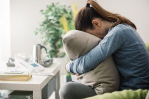 Depressed girl hugging her pillow.