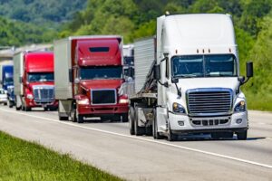 Group of trucks in convoy passing interstate.