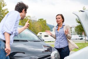 Woman driver and angry man arguing about the damage of the car.