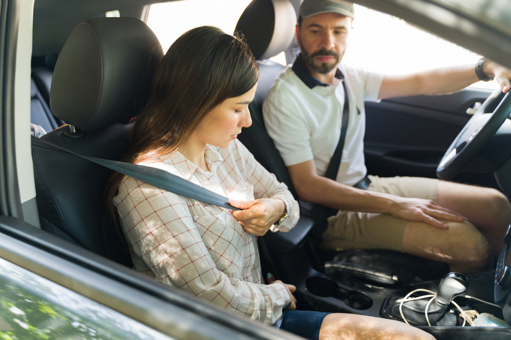 Woman in the front seat buckling seatbelt.