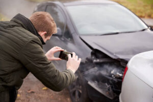 Driver taking photo of car accident on mobile phone.