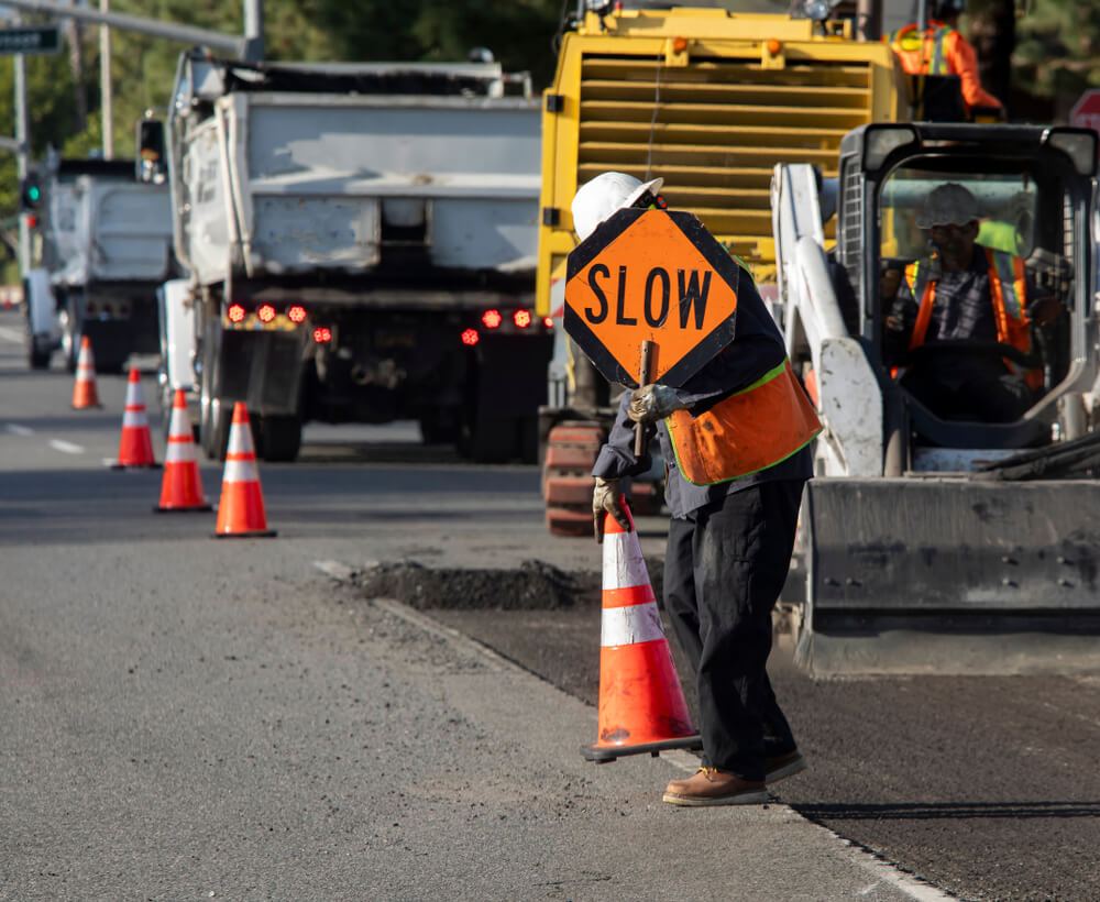 Road maintenance worker putting slow down to caution cars.