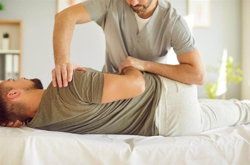 Chiropractor or osteopath specialist works with adult man in manual therapy office.