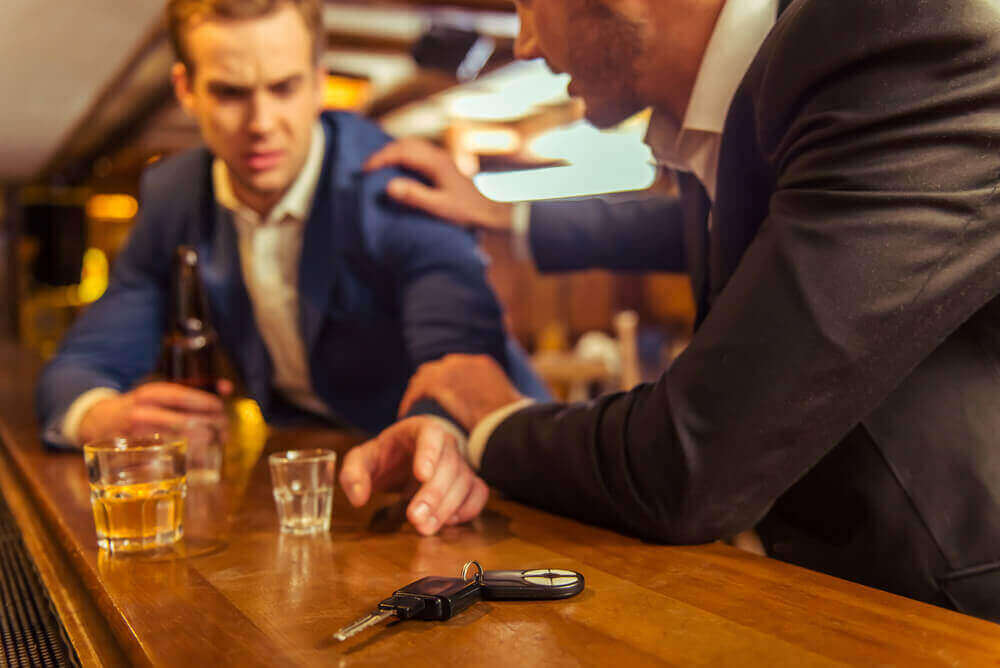 Drunk at a bar or dram shop reaching for his car keys.