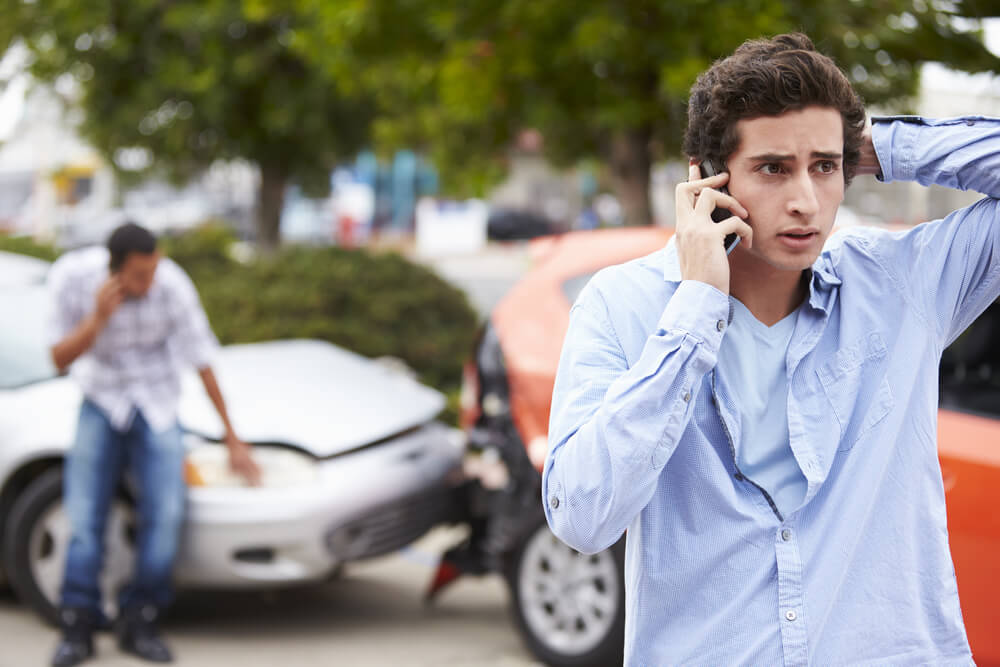 Worried teen driver calling his parents to report the accident.