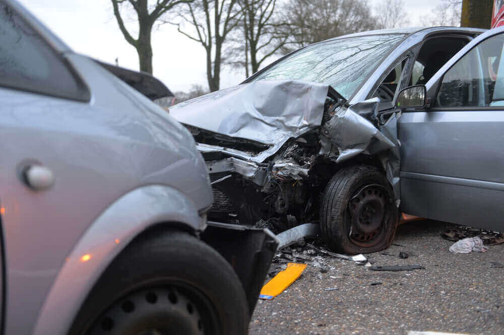 Cars severely damaged in a collision near highway.