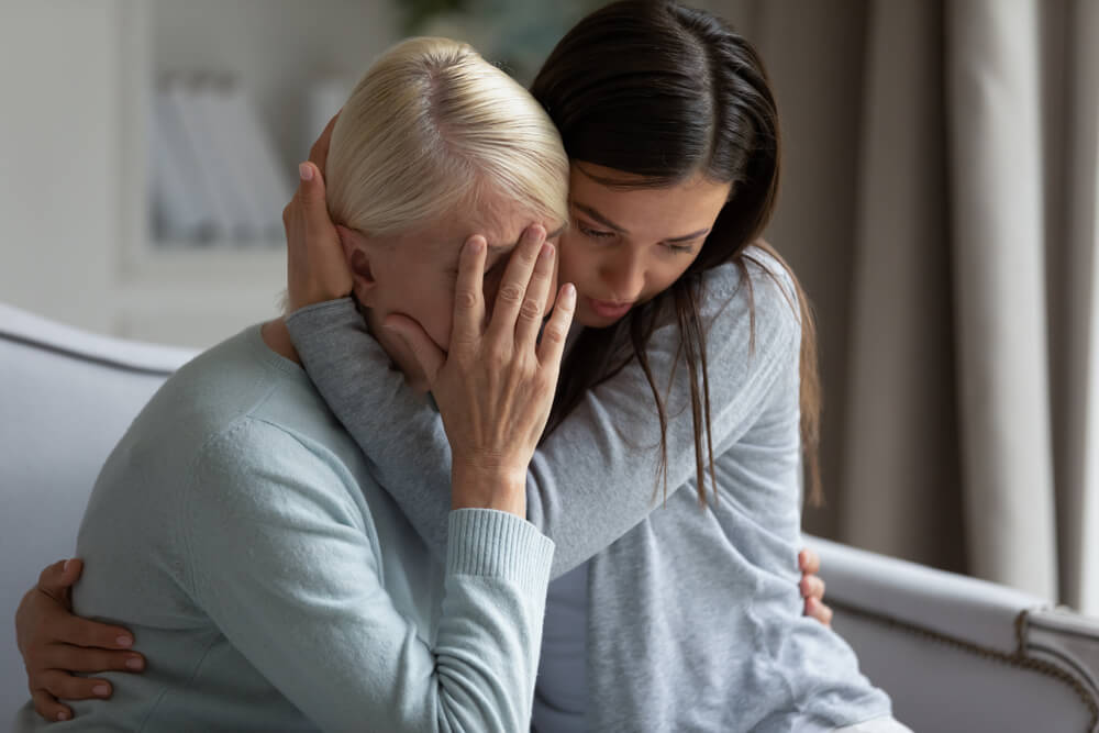 Close up caring grownup daughter comforting sad mother.