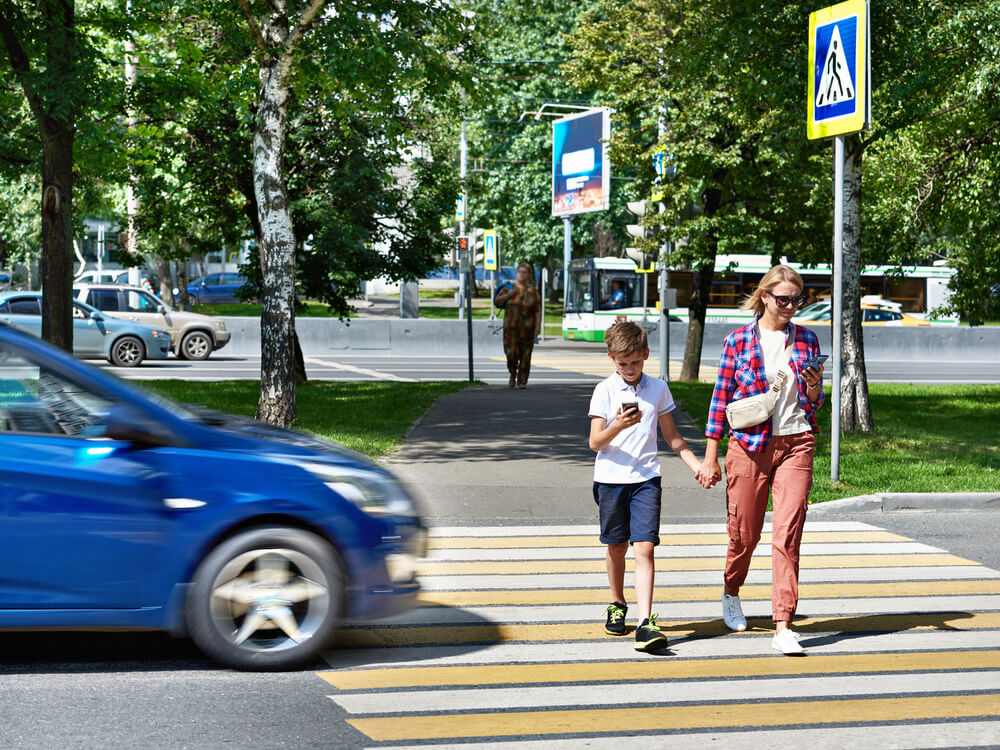 Mother and son crossing pedestrian lane with a speeding car.